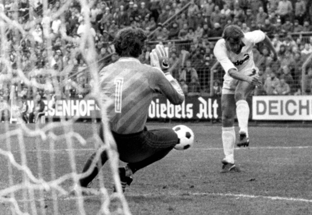 Bereits am 23. März 1985 beim 7:0 Erfolg gegen den 1.FC Kaiserslautern, feiert bei Borussia Mönchengladbach das neue Trikotdesign für die Saison 1985/86 seine Bundesliga-Premiere. Noch fehlen die markanten schwarzen Schulterklappen. Dazu stimmen weitere Merkmale mit der späteren Trikotversion nicht überein. In dieser Rubrik zeichnen wir die Veränderungen bei einem der beliebtesten Trikots der Gladbach-Fans von vom ersten Auftritt bis zur späteren, meistgespielten, Version nach. Foto: Imago/Horstmüller