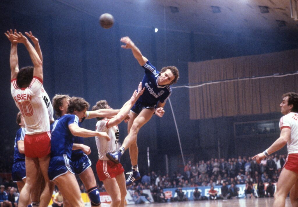 Neben Borussia im Fußball sponsert die Ruhrgas AG in den 1980er-Jahren auch zahlreiche weitere Top-Teams im deutschen Sport. Unter anderem den damaligen Rekordmeister im Handball, den VfL Gummersbach. Hier mit dem 124-maligen Nationalspieler Rüdiger Neitzel in einem Bundesliga-Spiel gegen TuSEM Essen im Jahr 1985. Foto: Imago/Werek